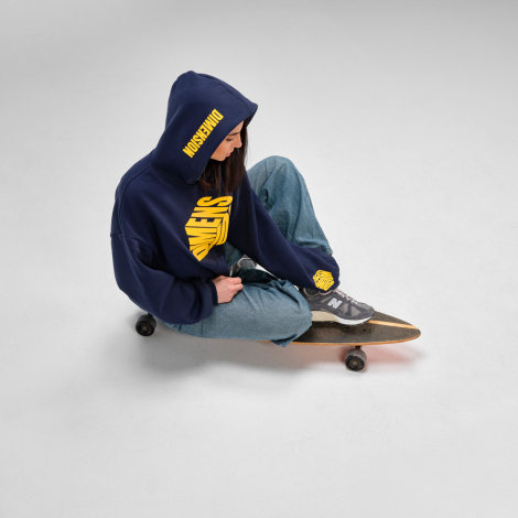 Femme portant un sweat à capuche oversize bleu marine avec un marquage visible sur le devant, la capuche et en bas de la manche 