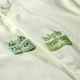 Gros plan comparant deux marquages en relief réalisés sur des t-shirts vert clair. Gros plan comparant deux marquages en relief réalisés sur des t-shirts vert clair.