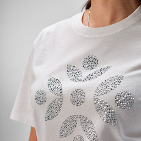 Gros plan sur un marquage visible en strass sur le devant d'un t-shirt blanc.