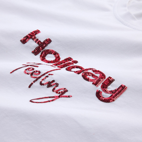 Gros plan sur un marquage visible en sequins rouges réalisé sur un t-shirt blanc.