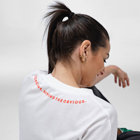 Vue de dos d'une femme portant un t-shirt oversize blanc avec un marquage visible au niveau de la nuque.