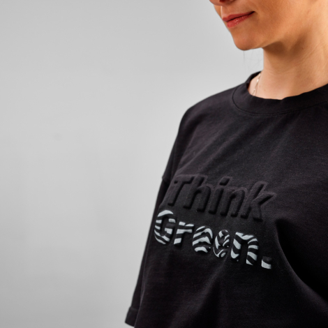 Gros plan sur le buste d'un t-shirt oversize noir avec un marquage visible au centre de la poitrine.