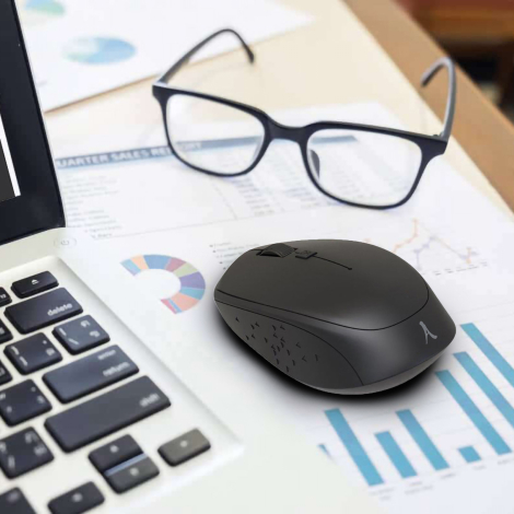 Souris sans fil noire en situation d’utilisation sur un bureau, à proximité d’un ordinateur portable, sans marquage publicitaire