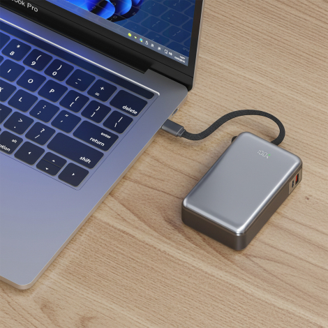 Batterie de secours reliée à un ordinateur portable par son câble intégré, illustrant son utilisation sur un poste de travail.