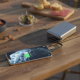 Batterie de secours reliée à un smartphone en situation d’utilisation nomade, sur une table en bois. Batterie de secours reliée à un smartphone en situation d’utilisation nomade, sur une table en bois.