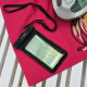 Pochette étanche avec smartphone en situation d’utilisation, posée sur une serviette à proximité d’un équipement de baignade. Pochette étanche avec smartphone en situation d’utilisation, posée sur une serviette à proximité d’un équipement de baignade.