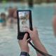 Pochette étanche utilisée à la piscine, permettant de manipuler le smartphone à travers la fenêtre transparente. Pochette étanche utilisée à la piscine, permettant de manipuler le smartphone à travers la fenêtre transparente.
