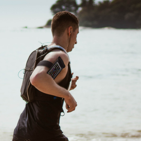 Pochette étanche portée au bras pendant une activité sportive en extérieur, avec smartphone visible à travers la fenêtre transpa