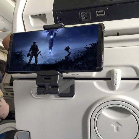 Support installé sur un siège d’avion et maintenant un smartphone en position horizontale, sans marquage visible.