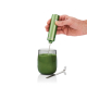 Mousseur électrique vert tenu à la main au-dessus d’un verre rempli d’une préparation verte homogène, avec cuillère métallique p Mousseur électrique vert tenu à la main au-dessus d’un verre rempli d’une préparation verte homogène, avec cuillère métallique p