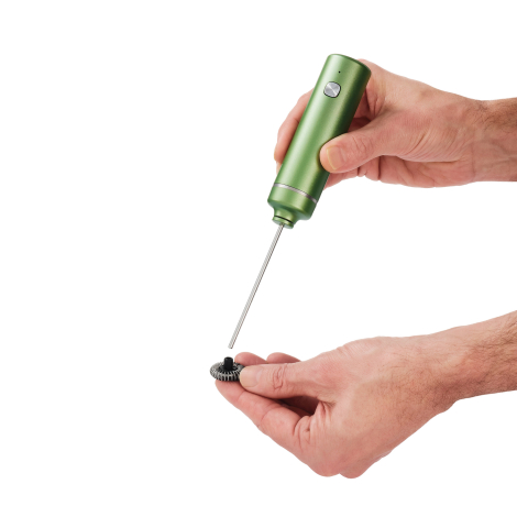 Mousseur électrique vert tenu d’une main, avec tige métallique séparée de son fouet circulaire présenté dans l’autre main.
