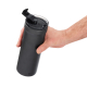 Mug isotherme noir tenu à une main et vu légèrement de dessus, avec couvercle transparent et système d’ouverture relevé.