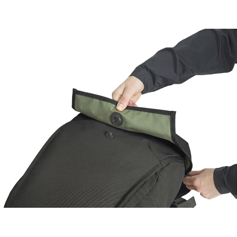 Détail du rabat supérieur d’un sac à dos noir ouvert par une personne, montrant son système de fermeture circulaire.