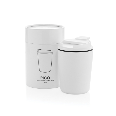 Tasse à café blanche avec couvercle posée devant sa boîte cylindrique assortie, décorée d’un dessin représentant la tasse et de 