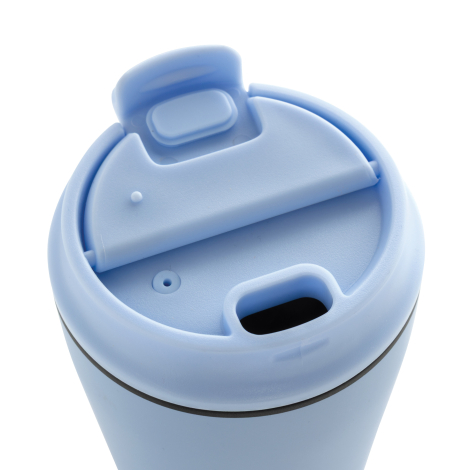 Gros plan en vue plongeante sur le couvercle bleu clair d’une tasse à café, montrant l’ouverture pour boire et le système de fer