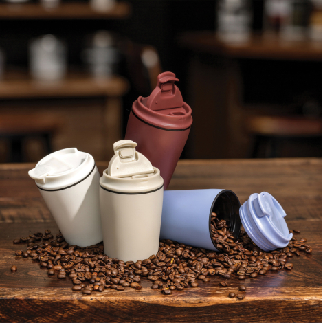 Mise en scène de quatre tasses à café blanches, beige, rouge et bleu clair sur une table en bois couverte de grains de café, don