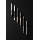 Composition de six stylos à bille disposés verticalement sur fond noir, présentant plusieurs associations de teintes sombres et 