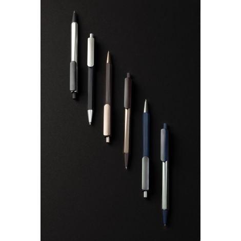 Composition de six stylos à bille disposés verticalement sur fond noir, présentant plusieurs associations de teintes sombres et 