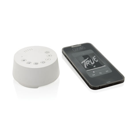 Enceinte à bruit blanc blanche posée à côté d’un smartphone affichant un lecteur audio, avec boutons de commande et indicateurs 