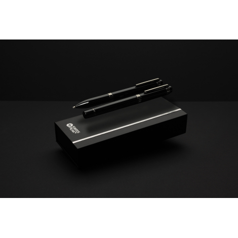 Stylo à bille et roller noirs posés en diagonale sur un coffret noir rectangulaire, avec clips et bagues métalliques argentés vi