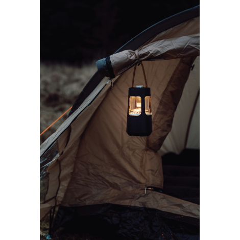 Lanterne de camping suspendue à l'entrée d'une tente et diffusant une lumière chaude, avec poignée de suspension en corde dans u