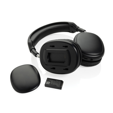 Casque audio noir ouvert et posé sur le côté, avec cache extérieur d’un écouteur retiré pour révéler le logement de la batterie,