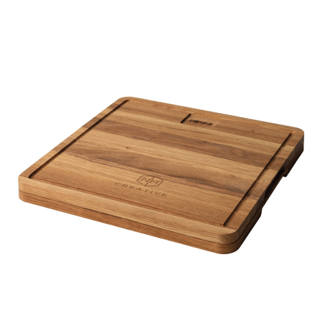 Planche à découper carrée en bois vue de trois quarts, avec rainure périphérique et marquage gravé dans la partie basse de la su