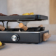 Gros plan sur la façade de l’appareil à raclette, avec bouton de réglage circulaire, poêlons à manches en bois et poignée latéra Gros plan sur la façade de l’appareil à raclette, avec bouton de réglage circulaire, poêlons à manches en bois et poignée latéra