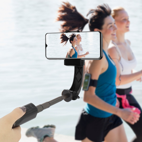Perche à selfie noire tenue à la main et déployée avec un smartphone en position horizontale, dans une scène de course à pied. A
