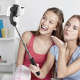Perche à selfie noire déployée et tenue à la main, avec un smartphone en position horizontale, utilisée par deux personnes pour Perche à selfie noire déployée et tenue à la main, avec un smartphone en position horizontale, utilisée par deux personnes pour