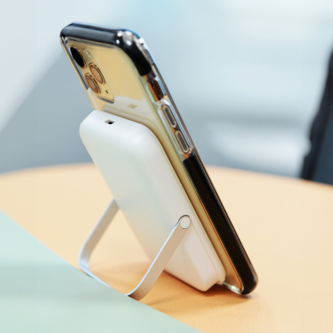Batterie fixée au dos d’un smartphone avec son support rabattable déployé pour maintenir l’appareil incliné.