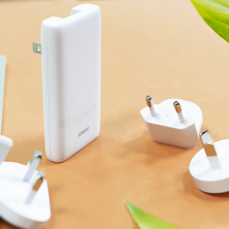 Mise en situation du chargeur 65 W avec plusieurs adaptateurs de prises interchangeables disposés autour du produit.