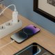 Chargeur secteur blanc branché sur une multiprise et relié par un câble à un téléphone posé sur une surface en bois, avec un sec Chargeur secteur blanc branché sur une multiprise et relié par un câble à un téléphone posé sur une surface en bois, avec un sec