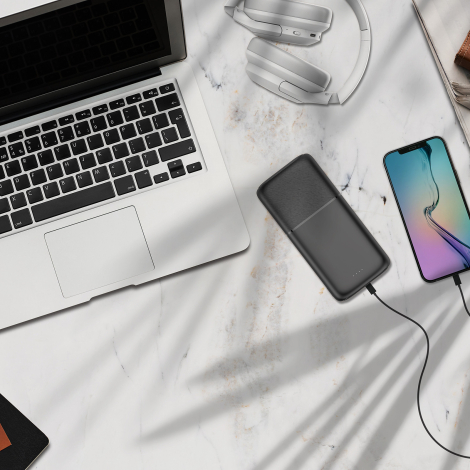 Batterie externe rechargeant un smartphone sur un bureau.