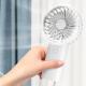 Ventilateur tenu à la main en fonctionnement, illustrant son utilisation comme ventilateur personnel portable. Ventilateur tenu à la main en fonctionnement, illustrant son utilisation comme ventilateur personnel portable.