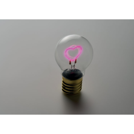 L’ampoule est allumée dans une ambiance sombre, son filament en forme de cœur diffusant une lumière rose au centre du globe tran