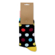Chaussette noire à pois multicolores présentée suspendue à une étiquette en papier kraft, avec bord-côte rose et pointe jaune. Chaussette noire à pois multicolores présentée suspendue à une étiquette en papier kraft, avec bord-côte rose et pointe jaune.