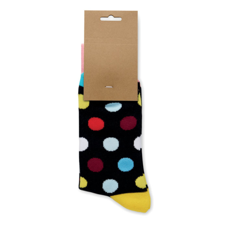 Chaussette noire à pois multicolores présentée suspendue à une étiquette en papier kraft, avec bord-côte rose et pointe jaune.
