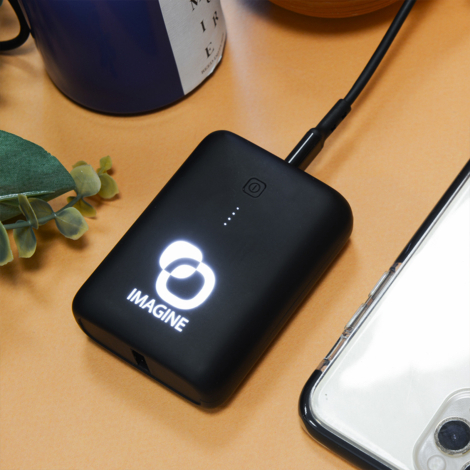 Batterie au logo lumineux près d’un smartphone.