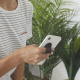 Support smartphone noir fixé au dos d’un téléphone et utilisé comme poignée de maintien par une personne.