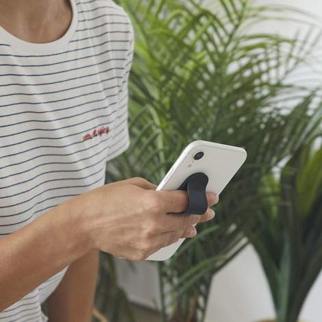 Support smartphone noir fixé au dos d’un téléphone et utilisé comme poignée de maintien par une personne.
