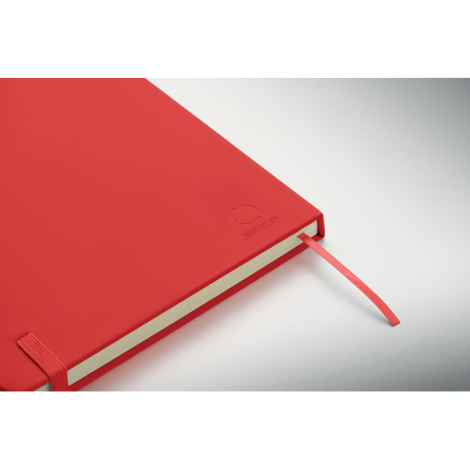 Gros plan sur un carnet rouge fermé, mettant en évidence la couverture rigide, l’élastique de maintien, le ruban marque-page et 