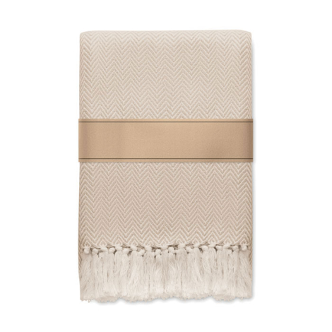 Présentée pliée de face, la couverture beige laisse apparaître son motif en chevrons sur toute la surface, ses franges alignées 
