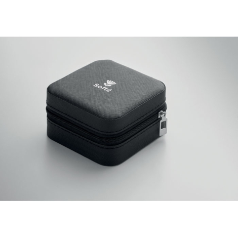 La boîte à bijoux noire est présentée fermée, sous la forme d’un petit coffret carré aux angles arrondis, avec une fermeture zip