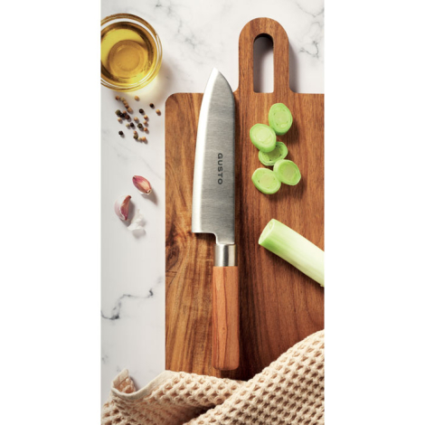 Couteau de chef posé sur une planche à découper en bois avec des rondelles de poireau ; exemple de personnalisation visible sur 