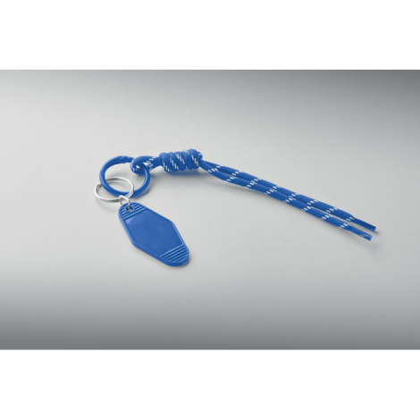 Porte-clés bleu posé à plat, composé d’un cordon tressé à motifs blancs noué, de deux anneaux et d’une étiquette colorée.