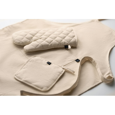 Vue rapprochée d’un tablier beige avec un gant de cuisine et une manique assortis posés dessus, tous deux ornés de coutures en l