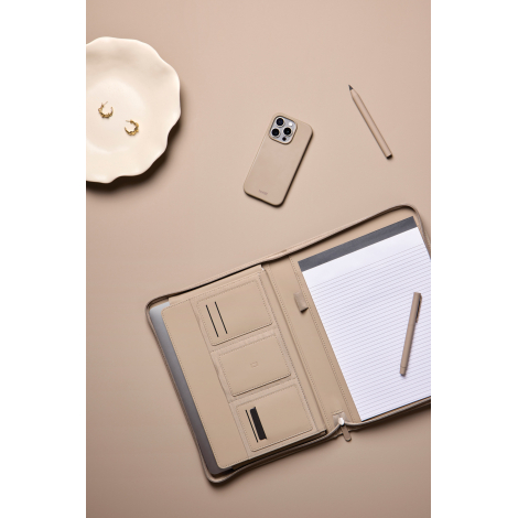 Porte-documents beige ouvert mis en scène sur un bureau, avec bloc-notes ligné, stylo, ordinateur portable et rangements intérie