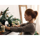 Une femme tient l’ampoule décorative à filament en forme de sapin dans un intérieur agrémenté d’un sapin de Noël, de bougies et Une femme tient l’ampoule décorative à filament en forme de sapin dans un intérieur agrémenté d’un sapin de Noël, de bougies et