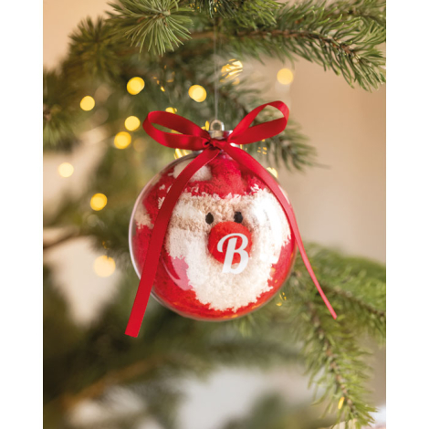 Boule transparente suspendue à une branche de sapin, avec les chaussettes Père Noël visibles à l’intérieur et un marquage blanc 
